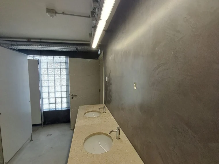 Corredor de sanitários com parede em microcimento escuro
